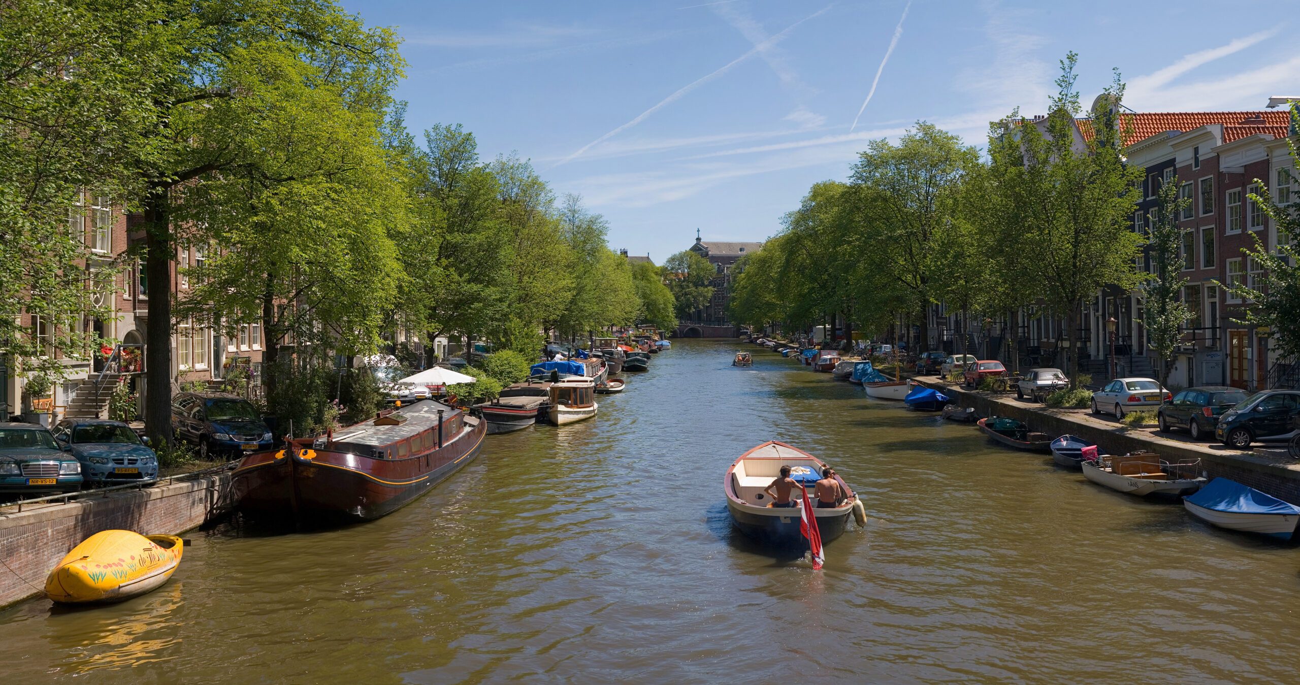 Small boat on an Amsterdam canal with bridges and canal houses