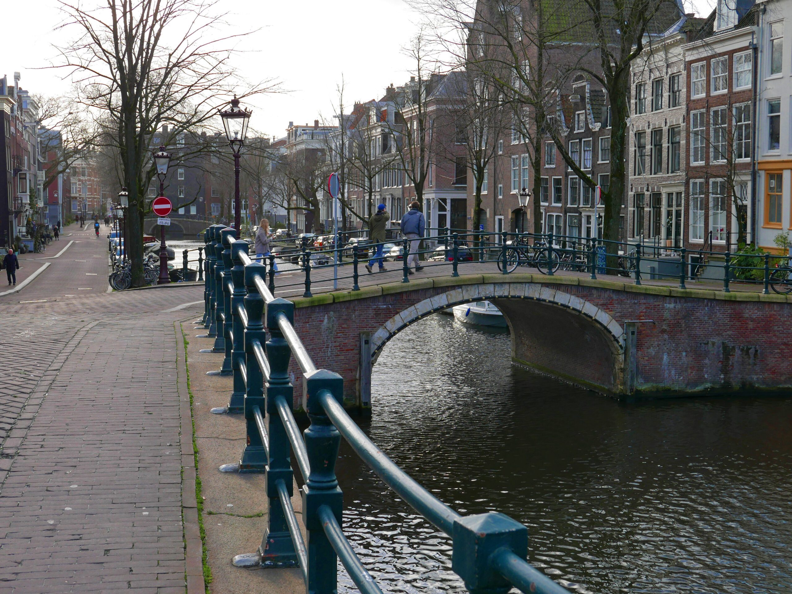 Old brick bridge over the Reguliersgracht canal in Amsterdam, with canal houses and trees along the water