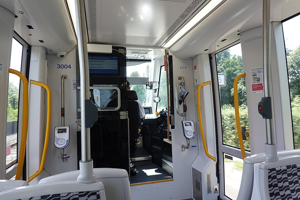 Interior de un tranvía GVB 15G con lectores de tarjetas junto a las puertas y la cabina del conductor al fondo