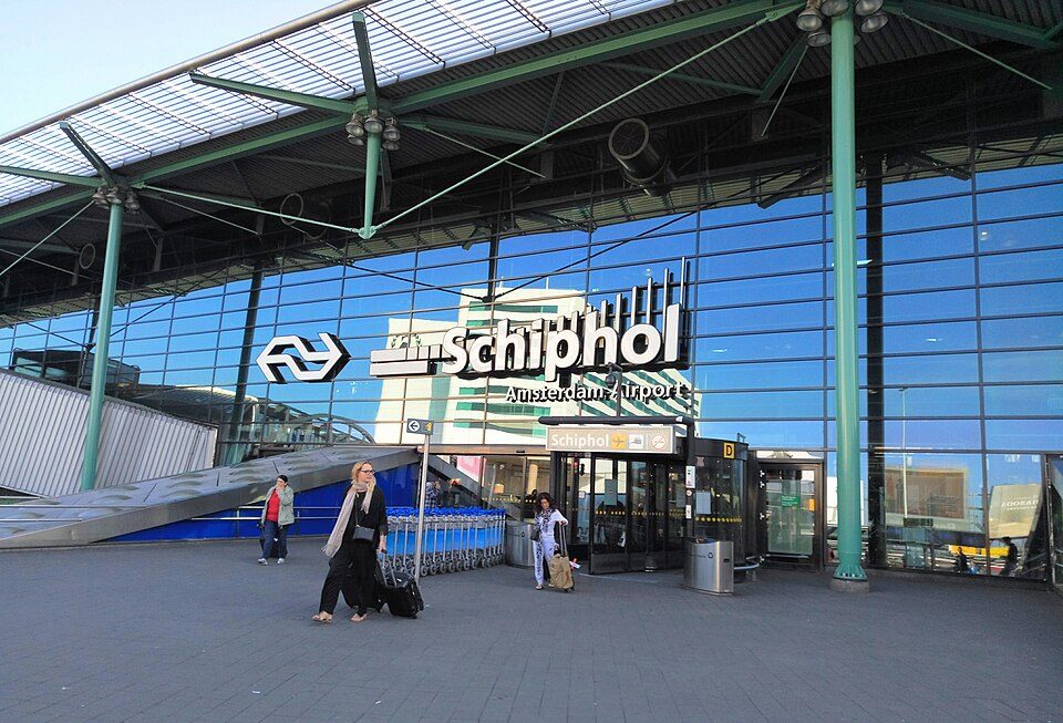 Entrada principal de Schiphol Plaza en el aeropuerto de Ámsterdam-Schiphol, viajeros con equipaje bajo la marquesina de cristal