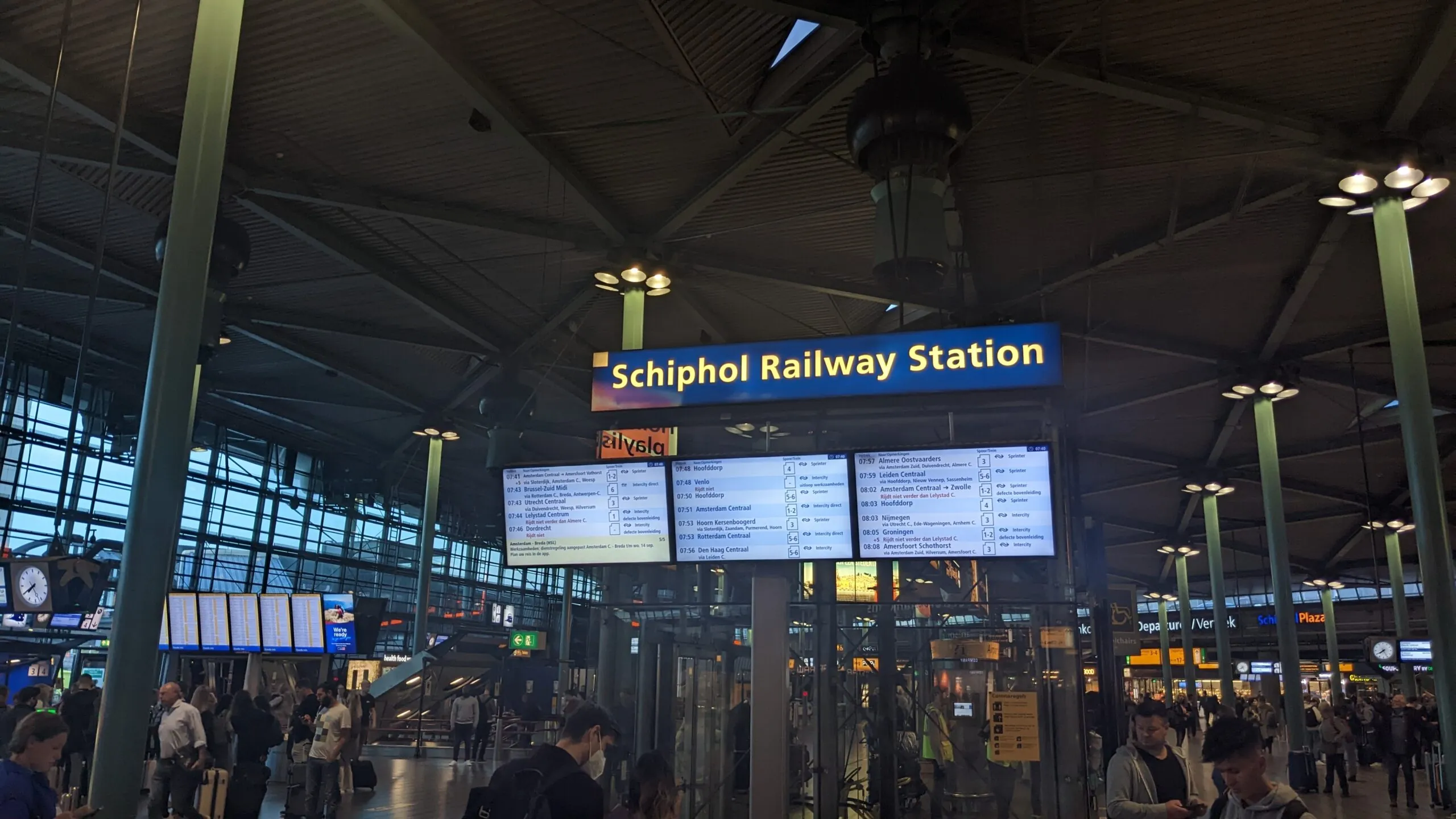 Blaues Schild Schiphol Railway Station über den Abfahrtsanzeigen in der Schiphol Plaza am Flughafen Amsterdam